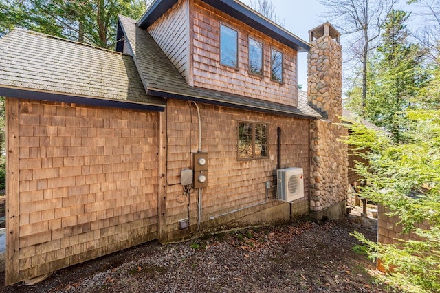 view of property exterior with a shingled roof, ac unit, and a chimney
