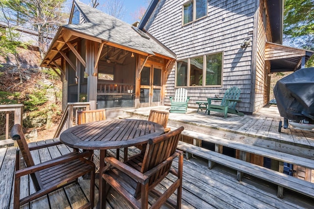 wooden terrace with outdoor dining area, a sunroom, and a grill