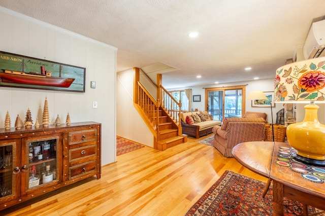 living room with stairway, a wall unit AC, recessed lighting, and wood finished floors