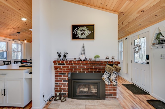 interior space featuring wood ceiling, baseboards, a brick fireplace, and light wood finished floors