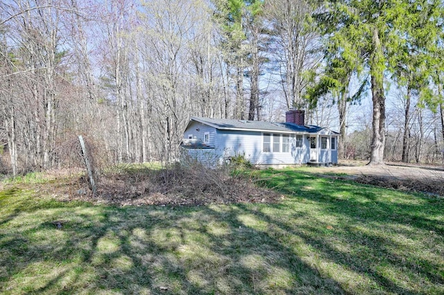 exterior space featuring a chimney, a sunroom, and a front lawn