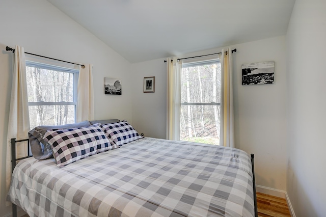 bedroom with baseboards, wood finished floors, and lofted ceiling