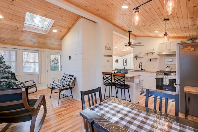 dining space featuring light wood-style floors, recessed lighting, vaulted ceiling with skylight, wooden ceiling, and a ceiling fan