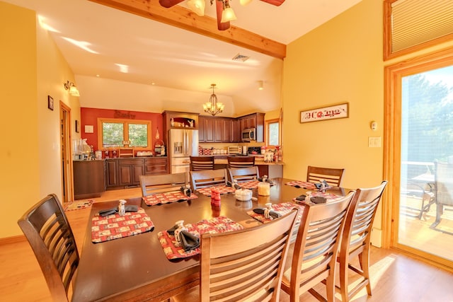 dining space featuring light wood-style floors, lofted ceiling with beams, ceiling fan with notable chandelier, and visible vents