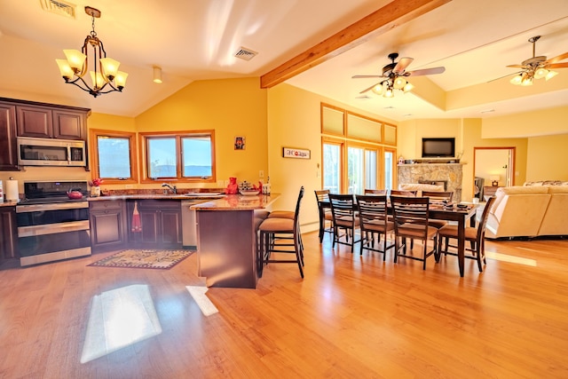 kitchen with appliances with stainless steel finishes, lofted ceiling, visible vents, and a kitchen bar