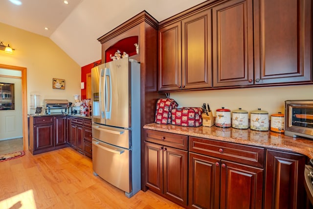 kitchen with light stone countertops, recessed lighting, stainless steel fridge with ice dispenser, light wood-style flooring, and vaulted ceiling