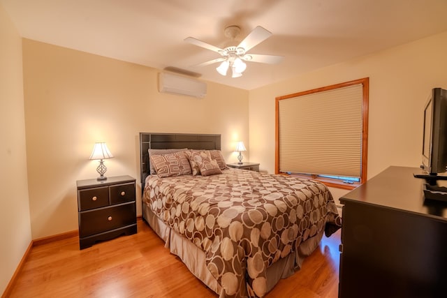 bedroom with light wood-style floors, a wall mounted air conditioner, baseboards, and a ceiling fan