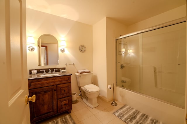 bathroom featuring tile patterned flooring, combined bath / shower with glass door, toilet, and vanity