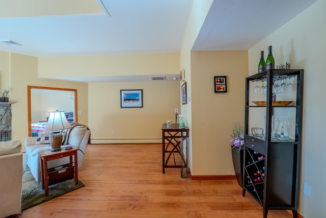 interior space with baseboards, baseboard heating, light wood-type flooring, and visible vents
