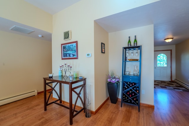 corridor featuring visible vents, a baseboard radiator, a baseboard heating unit, and wood finished floors