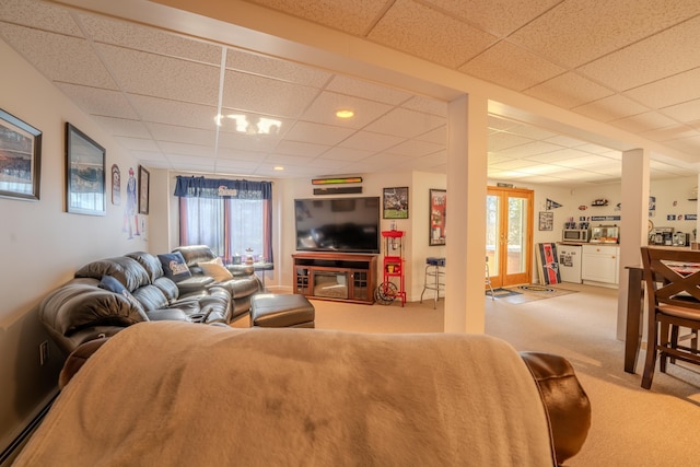 living area featuring carpet floors, a paneled ceiling, a baseboard heating unit, and a healthy amount of sunlight