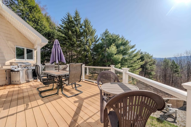 wooden terrace featuring a view of trees and outdoor dining space