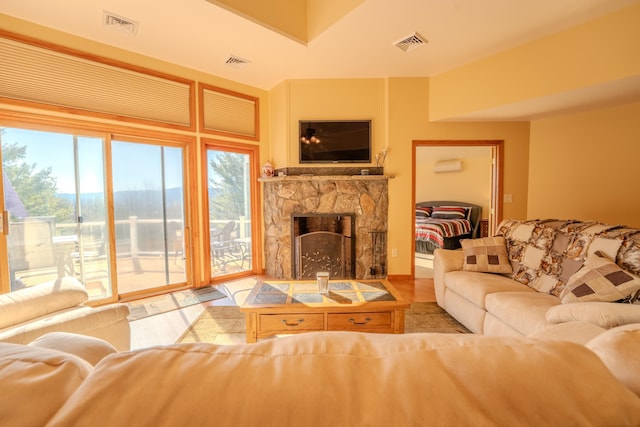 living room featuring visible vents, a stone fireplace, and wood finished floors