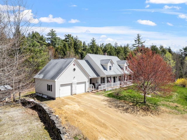 cape cod house with covered porch, a garage, a chimney, and dirt driveway