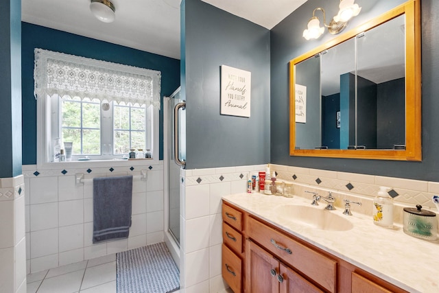 bathroom featuring wainscoting, vanity, tile patterned floors, tile walls, and a shower stall