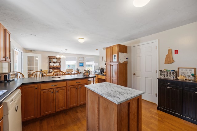 kitchen featuring white dishwasher, brown cabinetry, wood finished floors, and a peninsula