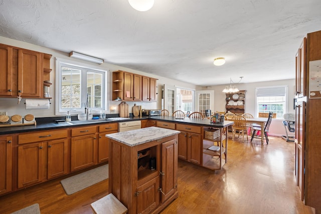 kitchen featuring a peninsula, open shelves, brown cabinetry, and dark wood-type flooring