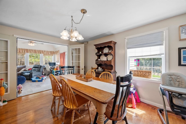 dining area with baseboards, light wood finished floors, and ceiling fan with notable chandelier