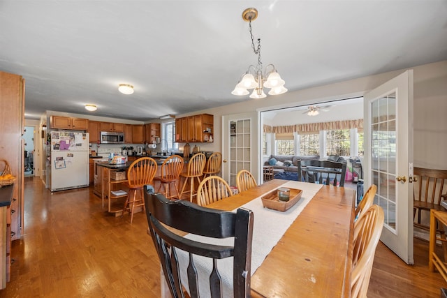 dining room featuring a healthy amount of sunlight, ceiling fan with notable chandelier, and wood finished floors
