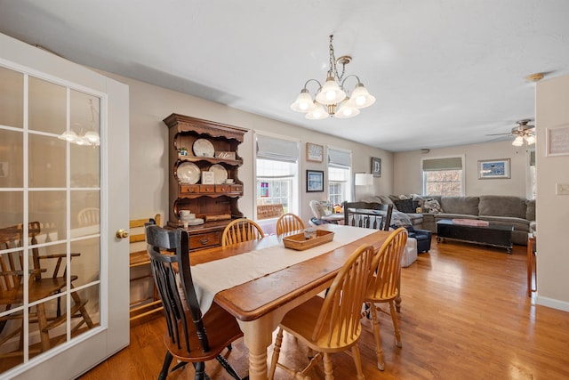 dining space with light wood-style flooring and ceiling fan with notable chandelier