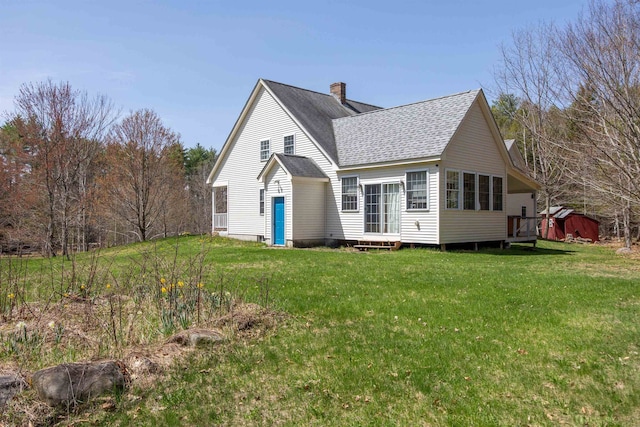rear view of property with a lawn, roof with shingles, a wooden deck, and a chimney