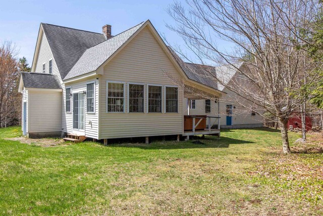 rear view of property featuring a shingled roof, a yard, a chimney, and entry steps