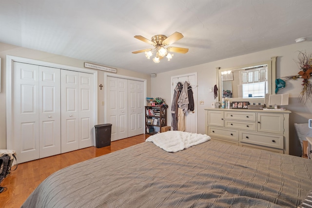 bedroom featuring multiple closets, a ceiling fan, and wood finished floors