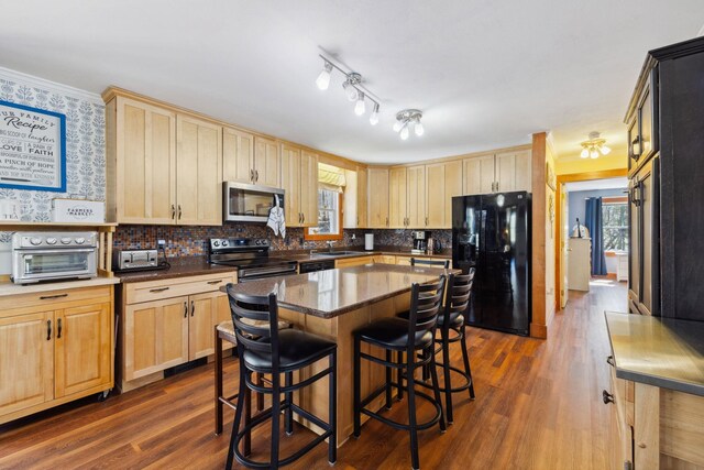 kitchen with a toaster, a kitchen bar, black appliances, and light brown cabinets