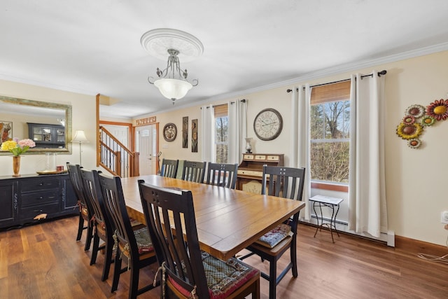 dining area featuring crown molding, stairway, baseboard heating, and wood finished floors