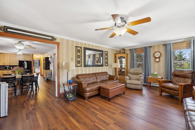 living room with ornamental molding, ceiling fan, dark wood-style flooring, and wallpapered walls