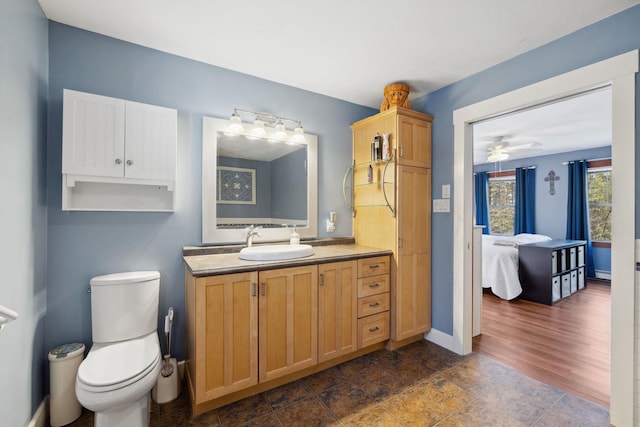 ensuite bathroom featuring toilet, baseboards, ensuite bathroom, and vanity