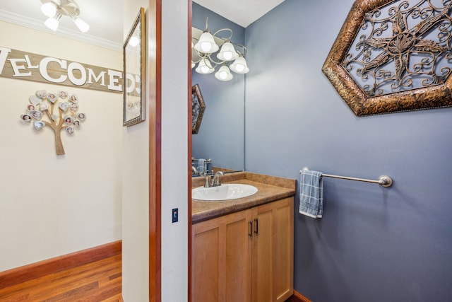 bathroom featuring crown molding, vanity, baseboards, and wood finished floors