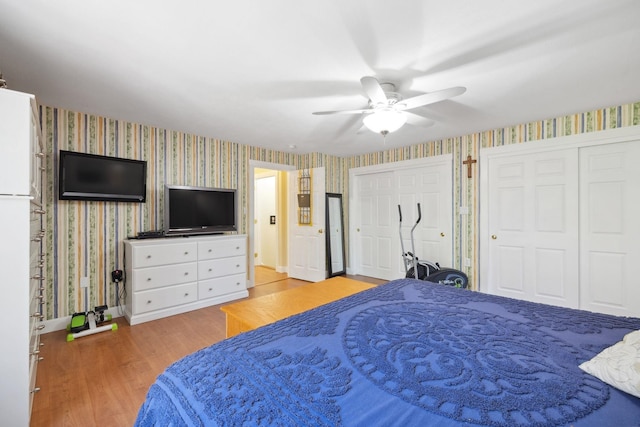 bedroom with two closets, wallpapered walls, baseboards, and wood finished floors