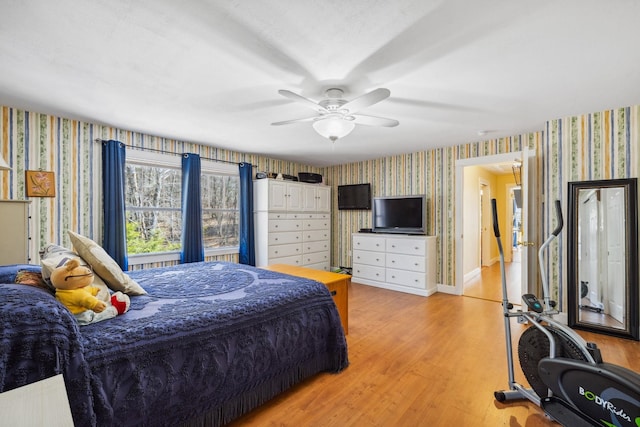 bedroom with light wood-style floors, ceiling fan, and wallpapered walls