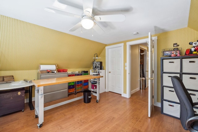 office area with light wood-type flooring, a ceiling fan, lofted ceiling, and wallpapered walls
