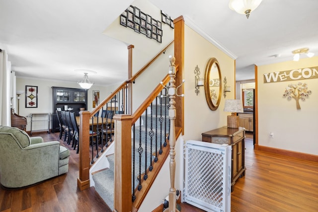 stairway with crown molding, baseboards, heating unit, and wood finished floors