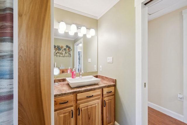 bathroom with vanity, ornamental molding, baseboards, and wood finished floors