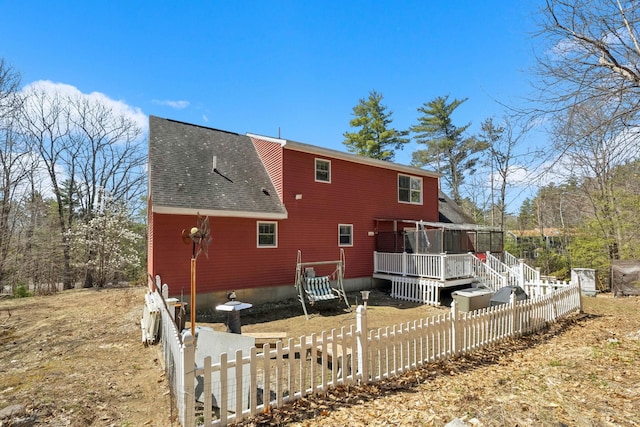 back of house featuring a shingled roof, fence, and a deck