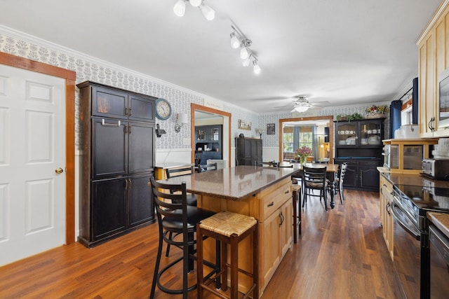 kitchen featuring ceiling fan, a kitchen bar, wallpapered walls, black electric range, and dark wood finished floors