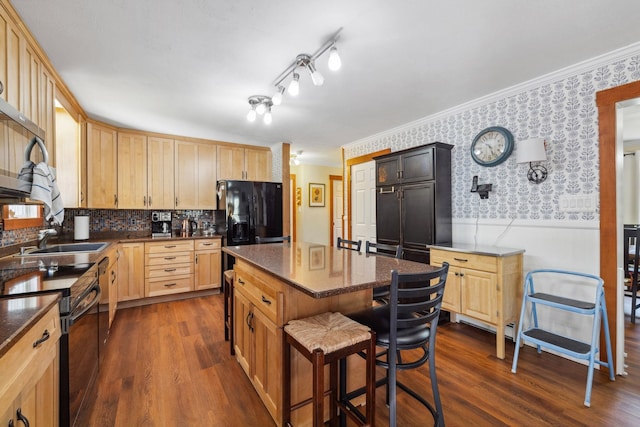 kitchen with wainscoting, wallpapered walls, dark wood-type flooring, a sink, and black appliances