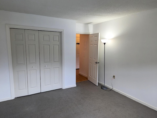 264 Main St Unit Q 31, Lincoln, NH 03251 - unfurnished bedroom featuring baseboards, a closet, dark carpet, and a textured ceiling