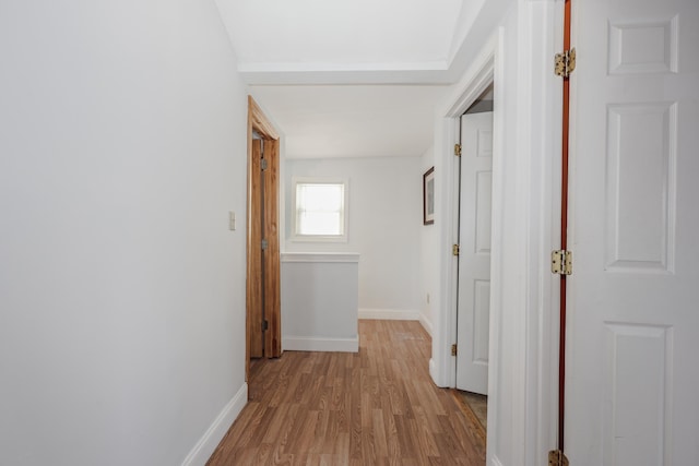 corridor with baseboards and light wood-type flooring