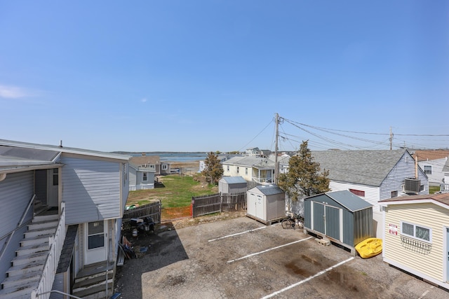 view of patio with fence, a storage unit, entry steps, an outbuilding, and a residential view