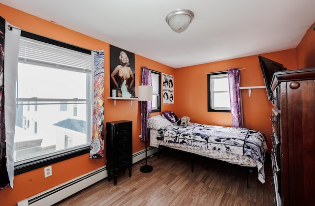 bedroom featuring baseboards, a baseboard heating unit, and wood finished floors