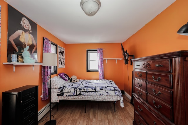 bedroom featuring baseboards, a baseboard heating unit, and wood finished floors