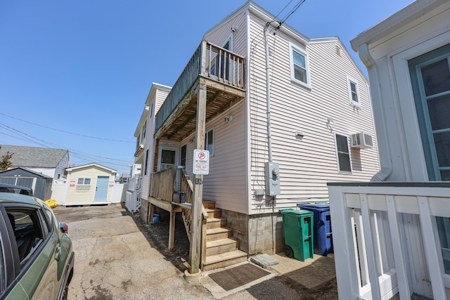 view of home's exterior with a balcony and a wall mounted air conditioner