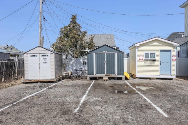 view of parking with fence and a shed