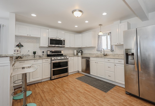 kitchen featuring white cabinets, appliances with stainless steel finishes, a sink, and light wood-style floors