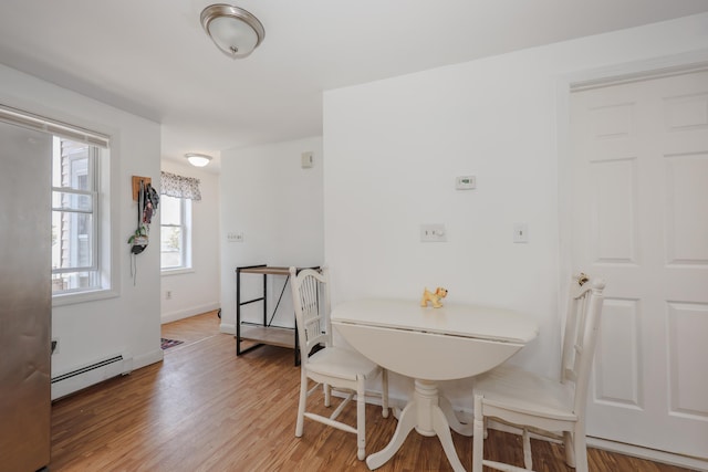 dining area with baseboards, baseboard heating, and light wood-type flooring