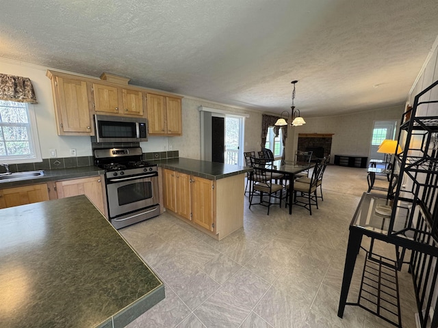 kitchen featuring a textured ceiling, a sink, a peninsula, ornamental molding, and stainless steel appliances